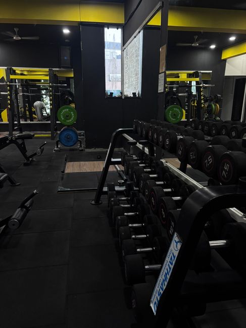 Mirrored corner with dumbbells for form checking during workouts at Tathhastu Fitness